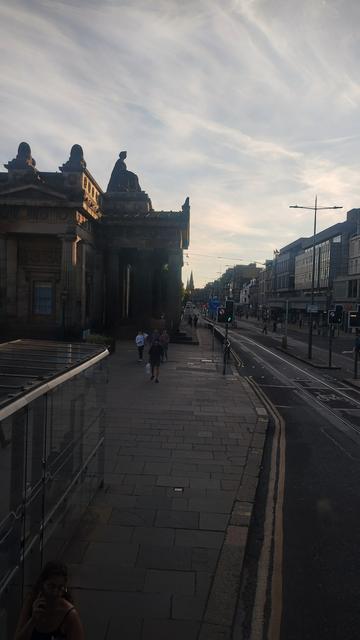 View from front of upper deck of a double decker bus, looking west along Princes Street as sunset approaches, past the Mound and the Royal Scottish Academy