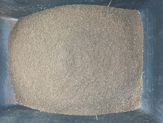 A black bin full of a brown soil-like substance.