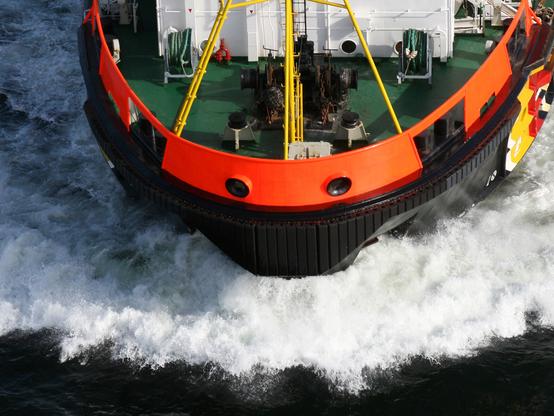 Draufsicht aus der Luft auf den Bug eines Mehrzweckschiffes mit Bugwelle.