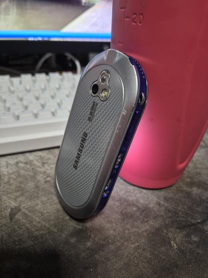 The back of a Samsung Beat DJ, the front is resting on a pink water bottle.