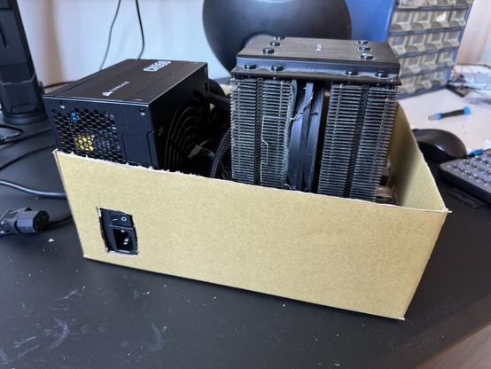 Picture of a power supply and motherboard/CPU snuggly fitting together in a cardboard box, with cutouts for IO and PSU