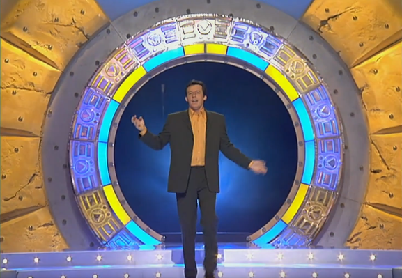 Jean-Luc Reichmann dans Attention à la marche! qui sort d’un truc qui ressemble à une porte des étoiles