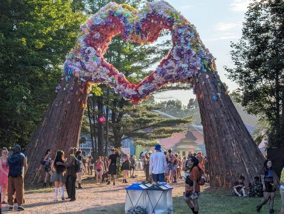 A large sculpture made of wood and flowers that depicts 2 hands making the 'heart' symbol.