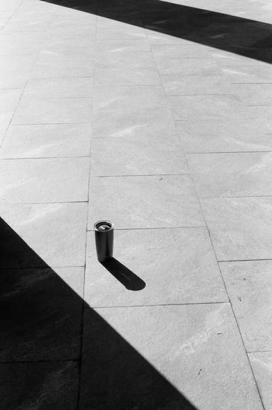 A lone tumbler style mug sit in the light with shadows cast by large pillars behind it.