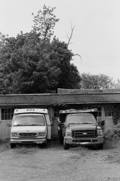 Two trucks sit in an old garage.