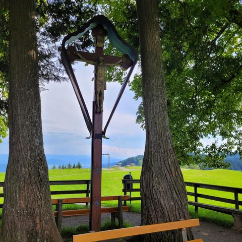 Großes Kreuz zwischen Linden auf dem Kreuzberg. Dahinter grüne Wiesen