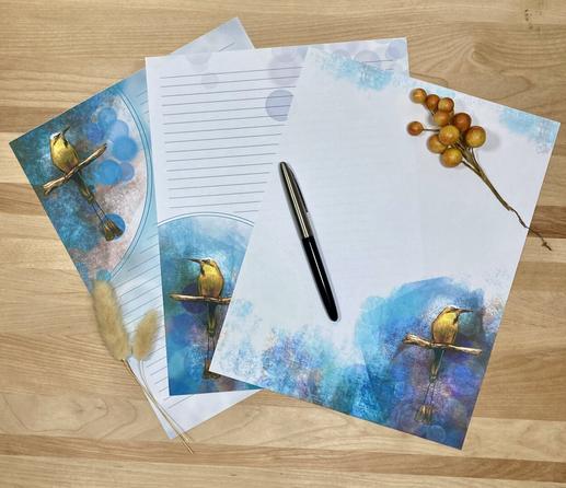 Photograph of three pieces of stationery paper on a wooden surface, posed with a pen and a sprig of berries.