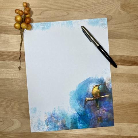 Photograph of a piece of stationery paper on a wooden surface, posed with a pen and a sprig of berries.