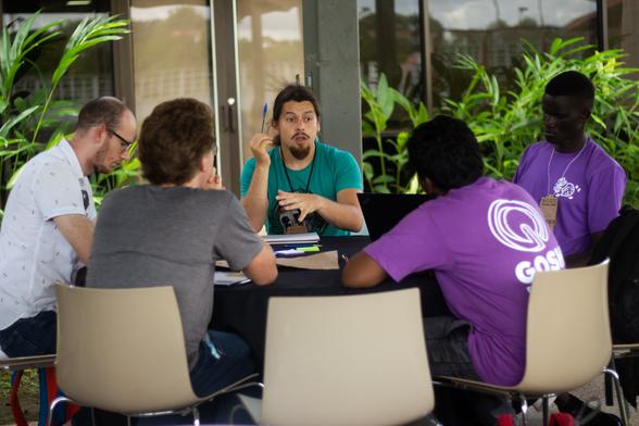 A meeting of 5 people sitting around a table discussing topics relevant to the GOSH community.