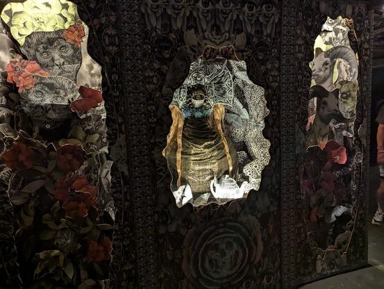 A dark indoor 'window' with floral and eyeball patterns.  Inside each window are collages of lions, monkeys and plants.
