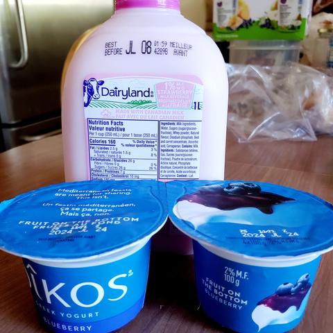 2 containers of Oikos blueberry yogurts - 100g, fruit on bottom.
1L jug of Dairyland 1% strawberry milk is behind the yogurts.