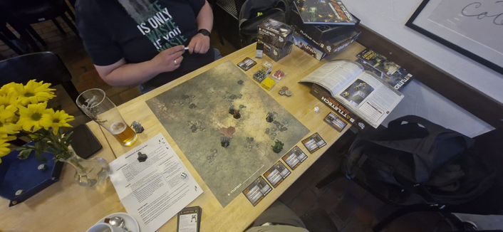 Ein Tisch auf mit BattleTech Büchern und Boxen, einen Blumenstrauß und einem Bierglas. In der Mitte eine Hexmap mit einigen Miniaturen. Es steht nur noch einer meiner bemalten Roboter auf dem Tisch. Ich habe verloren.