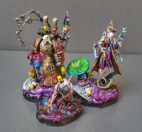 Three painted miniatures of Fabius Bile, Hexachires the Haemonculus and a random vatborn on very purple bases with skulls and mushrooms. The style is very painterly and not 'eavy metal at all.