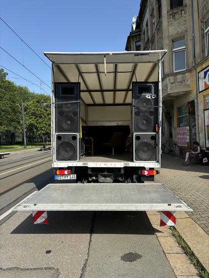 Ein 7,5 t LKW direkt von hinten fotografiert. Auf der Ladefläche stehen zwei große Lautsprechertürme.