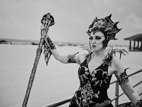 Participant in ornate costume at Mermaid Parade on Coney Island boardwalk, Brooklyn, expressing joy and celebration of cosplay and beach culture.