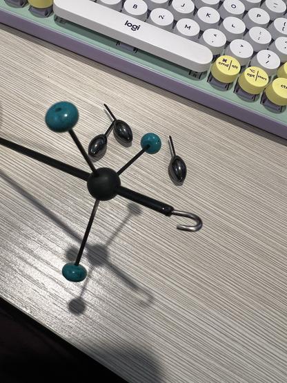 A small spindle (for handspinning yarns). This one is made by sticking a shaft through a rubber sphere which has holes drilled evenly around it. Triplets of weights on carbon-fibre pins are stuck into the sphere to make the spindle whorl.