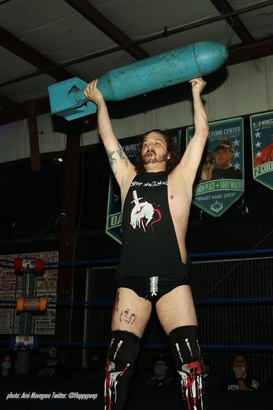 Wrestler Conor Claxton holding an old bomb in a wrestling ring