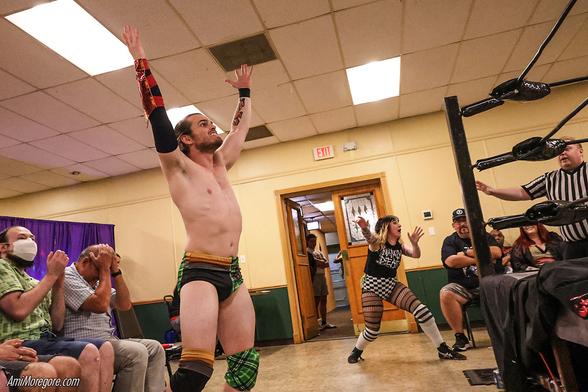 Wrestler Weber Hatfield holding an invisible bomb outside of the ring as fans, fellow wrestlers and the ref react in fear