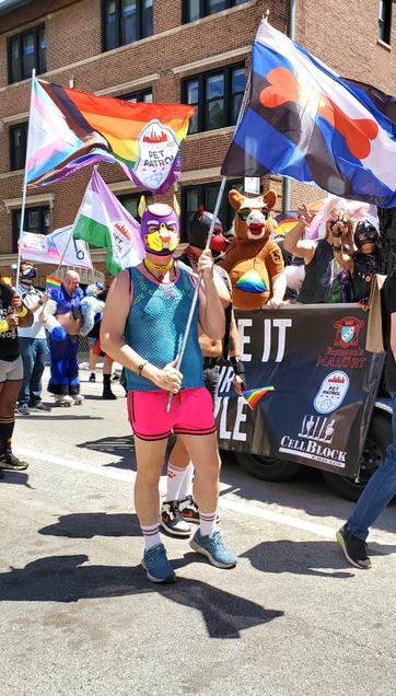 Fluster holding a puppy pride flag while marching at Chicago pride 2024