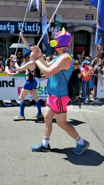 Fluster holding a puppy pride flag while marching at Chicago pride 2024