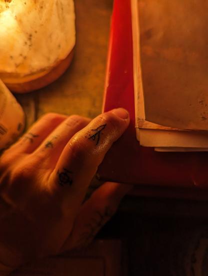 The focus of the image is a finger tattoo made up of fine black lines and three carefully placed dots. The lines evoke the sentiment of roots or lightning, a kind of fractal branching pattern in small space, but difficult to describe exactly.