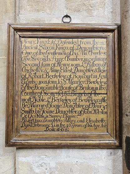 Photograph of a wooden board with a gold wash paint, and black lettering pained on it. Board is dated 1668, hung in Chichester Cathedral, writing is about Henry King defending these lands from the Amglo Saxons. The lettering is condensed, crowded. Good contrast and clearly painted.