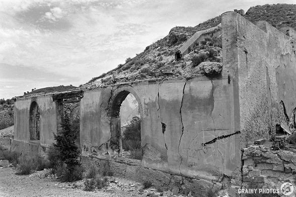 A black-and-white film photo of a wall of one of the abandoned buildings on the site.