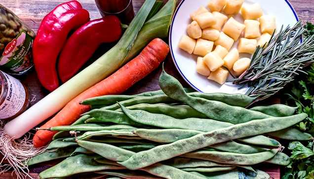 auf einem Brett das Gemüse, ein Glas Kapern, Rosenharissa im Glas, Gnocchi und Rismarinzweige auf einem Teller, daneben ein Bund glatte Petersilie