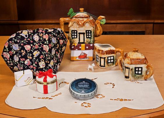 A tea tableau with a little tea set (teapot, creamer, sugar bowl) in the shape of thatched cottages. The tea is Earl Grey Imperial from Harney and Sons.