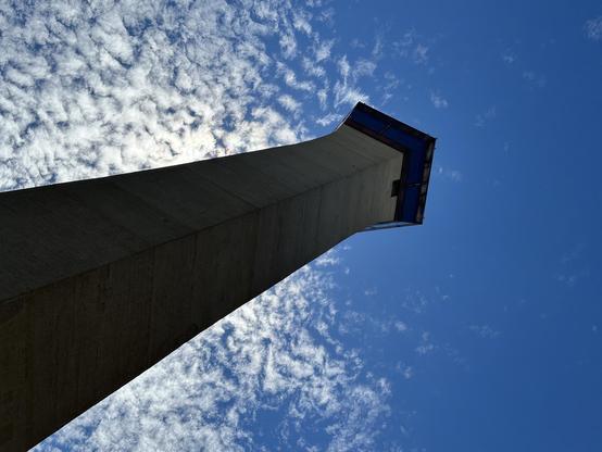A tall concrete tower against a blue sky with scattered clouds.
