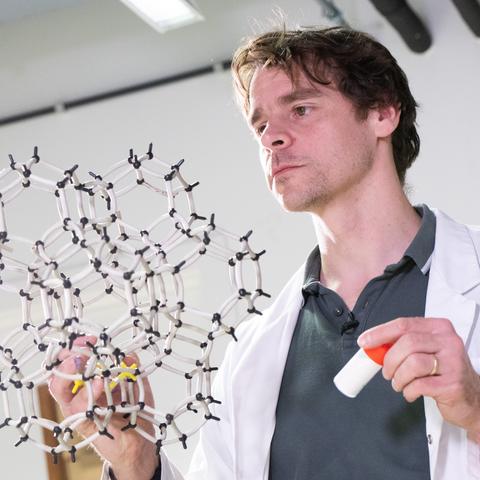A photo of a scientist working with a plastic model in his lab.