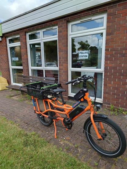 A bright orange, long tail electric bike parked up outside my polling station.
