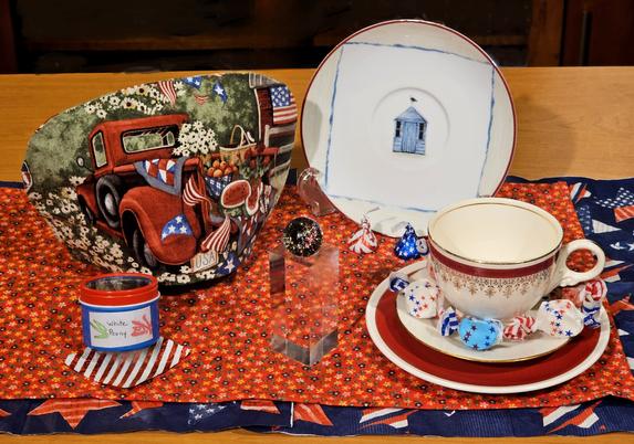 A tea tableau with traditional elements of Independence Day such as red, white, & blue, stars & stripes, flags, fireworks, and Americana. View it however you will, with or without irony.