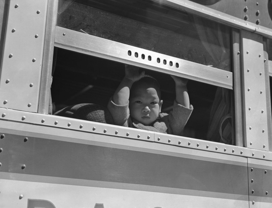 A child looks at the open window of a railway train on the way to an internment camp