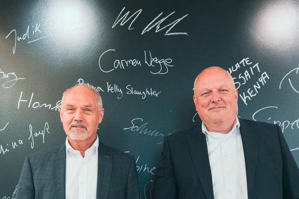 Ulrich Kelber mit seinem Stellvertreter, Jürgen Müller, vor einer Wand mit Namen und Unterschriften. Über den beiden ist neu die Unterschrift von Ulrich Kelber selbst zu sehen