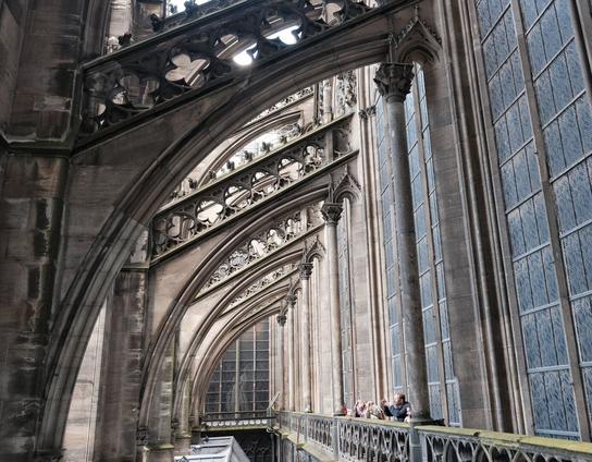 Blick von einer Balustrade außen auf Strebebögen und Fenster des Kölner Doms