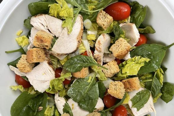 Ensalada de sobras de pollo asado con lechuga, espinacas tiernas, tomates miniatura, cebolleta, dados de pan y vinagreta.