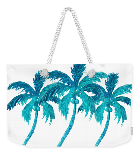 A white weekender tote bag with a painting of three coconut palm trees swaying in the breeze. There are coconuts at the top of the green palm trees and the background is white.