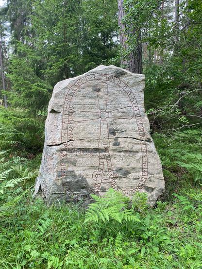 Photo he runestone Sö 34 with trees in tge background.