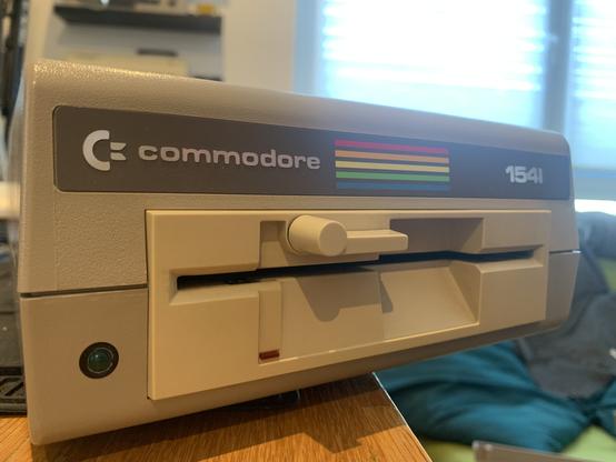 Closeup of the front of the drive showing the Commodore logo, rainbow and 1541 product number, as well as the white floppy drive mechanism.