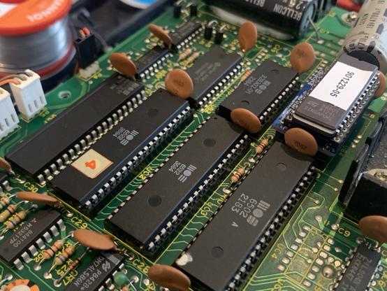 Close-up of a circuit board featuring multiple integrated circuits and capacitors.one 6502 CPU and two 6522 VIAs are visible.