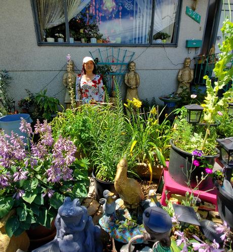 Mom standing amidst our Chinese themed front gardens. Wide shot.