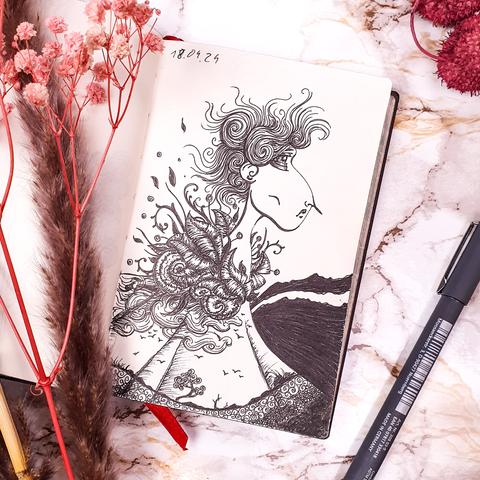 Sketchbook on a white marble surface. Around it some dried flowers and an inkpen. Inkpen sketch of a female presenting character wearing a dress with a landscape in it and leaves and flowers as a collar.