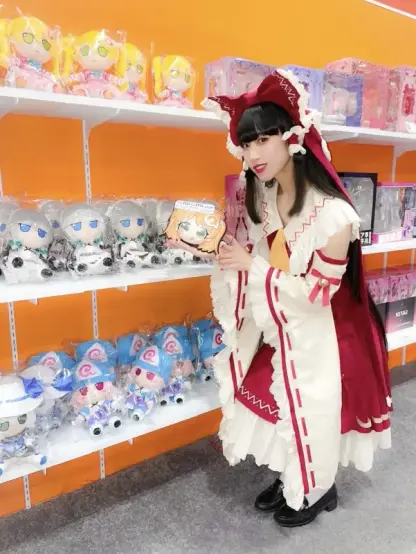 Hima cosplaying as Reimu Hakurei stands in front of shelves of anime merch