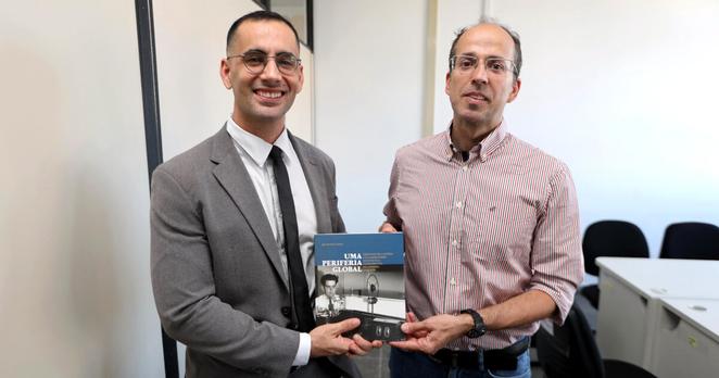 Quintino Lopes offering the book “Uma Periferia Global”, authored by him, to Alan Cedraz, coordinator of the Centre for the Defence of Historical, Artistic and Cultural Heritage.