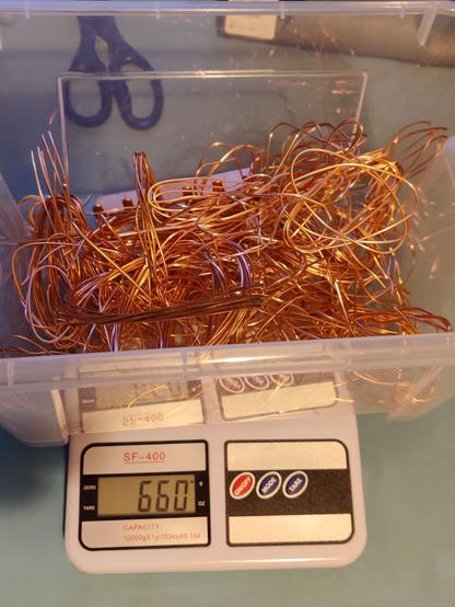 plastic tub sitting on scales full of twists of bright copper cables. the scales which have the tub weight cancelled out are showing 660 grams.