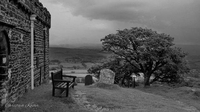 Part of the wall of the church St. Michael de Rupe with a bench and a tree (monochrome)