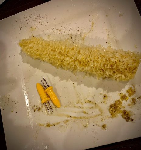 Empty cob of corn on plate with remnants of butter and pepper