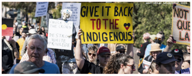 Demonstrant*innen mit Schildern, im Vordergrund eines mit der Aufschrift "Give it back to the indigenous" (Foto: Matt Hrkac, Melbourne 2022)