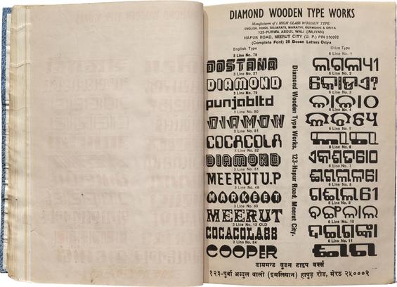 Photo of a book spread. Verso is blank. Recto has 20+ samples of type in Latin and Oriya scripts.